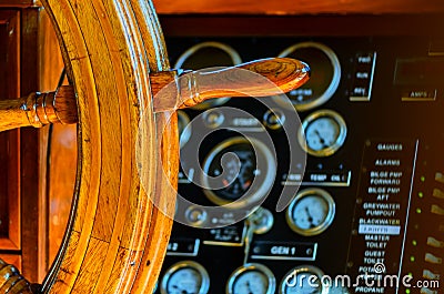 Yellow, old, lacquered, wooden steering wheel on a marine yacht, sensors and pointers with arrows in the background Stock Photo