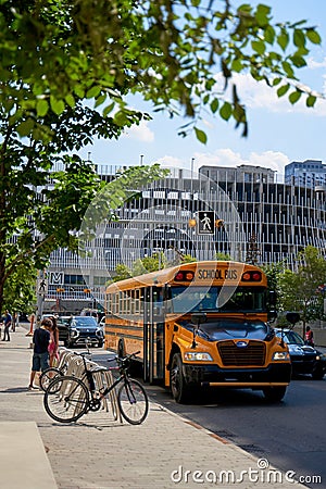 A yellow old school bus drives through the modern city of Calgary Editorial Stock Photo