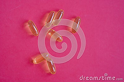Yellow omega 3 fish oil pills on a red background Stock Photo