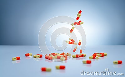 Yellow-orange capsules pill falling down on white table. Pharmaceutical industry. Tranexamic acid capsule pills for treatment Stock Photo