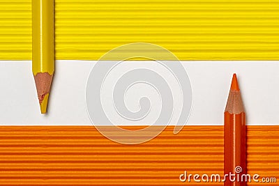 Yellow and orange pencils on colored paper sheets Stock Photo