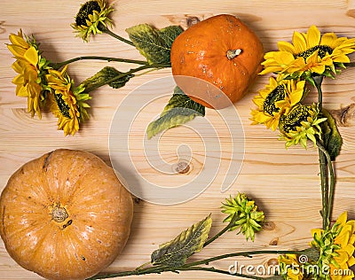 Yellow-orange pumpkins and sunflowers on a light wooden surface, Halloween and autumn harvest concept, farm product, vegetable Stock Photo