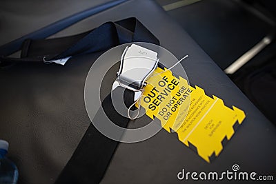 Yellow out of service warning sign tag attached on faulty damage defect plan safety seat belt Stock Photo