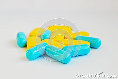 Yellow oval pills and blue capsules on white background side view Stock Photo