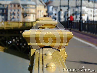 Yellow painted cast iron bridge railing in diminishing perspective with pedestrian Stock Photo