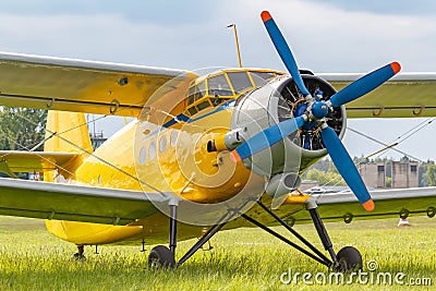 Yellow painted legendary soviet aircraft biplane Antonov AN-2 parked on a green grass of airfield closeup Stock Photo