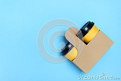 Yellow paper cups in craft cup holder and light blue background. Flatlay. Coffee to go concept. Place for text on the left. Copy Stock Photo