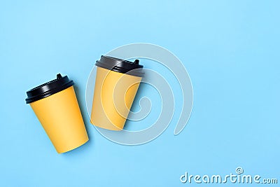 Yellow paper cups on a light blue background. Flatlay. Coffee to go concept. Place for text on the right. Copy space. Minimalism, Stock Photo