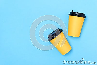 Yellow paper cups on a light blue background. Place for text on the left. Top view. Coffee to go. Copy space. Minimalism concept. Stock Photo