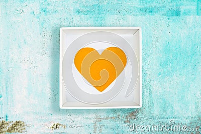 Yellow paper heart in white cardboard box on old turquoise metal background Stock Photo