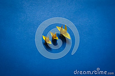 Yellow paper mother and baby birds on blue background. Stock Photo