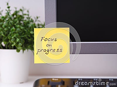 Yellow paper note with reminder Focus on Progress on it sticked on to a monitor Stock Photo