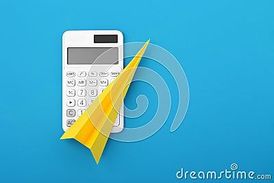 Yellow paper rocket on calculator on blue background Stock Photo