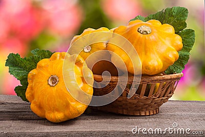 Yellow pattypan squash with leaf in a wicker basket on wooden table blurred background Stock Photo