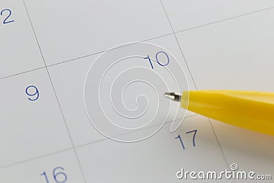 yellow pen points to the number 10 on calendar background. Stock Photo