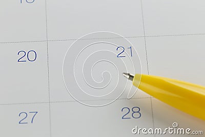 yellow pen points to the number 21 on calendar background. Stock Photo