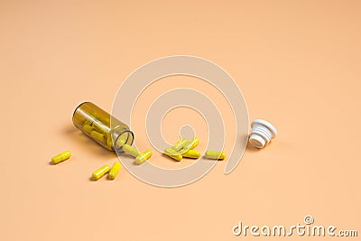 Yellow pills in the glass bottle on a orange background Stock Photo