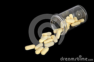 Yellow pills spilling out of a bottle Stock Photo