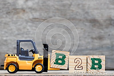Yellow plastic forklift hold letter B to complete B2B Stock Photo