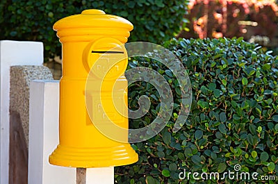 Yellow post box in green garden. Decorative postbox closeup photo. Vintage mail box and green hedge Stock Photo