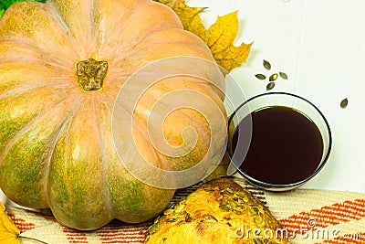 Yellow pumpkin, seeds, bread and oil in the bowl. Harvest on the table and fallen leaves. Autumn products Stock Photo