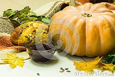 Yellow pumpkin, seeds, bread and oil in the bowl. Harvest on the table and fallen leaves. Fresh pumpking products Stock Photo