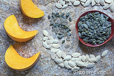 Yellow pumpkin slices and seeds - in shell and peeled. Large wooden spoon with peeled pumpkin seeds Stock Photo