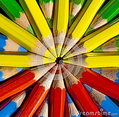 Yellow,red,blue and green colored pencils in the round formation on the black background close up . Stock Photo