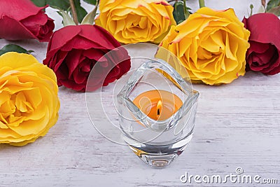 Yellow and red roses and candle on white wooden background Stock Photo