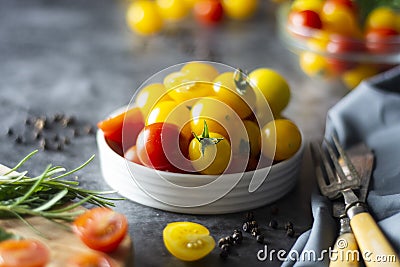 Yellow and red tomatoes in plate, isolated over dark background Stock Photo