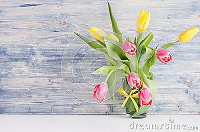 Yellow and red tulips in vase on blue shabby chic wood board. April spring background, home interior, decor. Stock Photo
