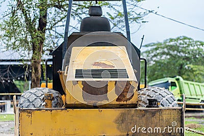 A yellow road roller that's on the stand by mode without the roll at a park Stock Photo
