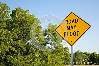 Road May Flood Sign In Spring With Green Trees And Clear Blue Sky Stock Photo