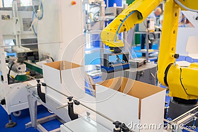 Yellow robotic arm manipulator working with cardboard boxes - sorting system Stock Photo