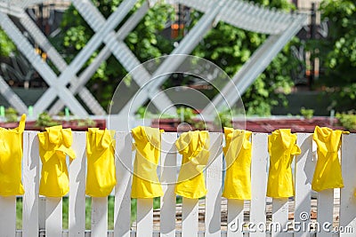 Yellow rubber gloves for work in a garden and a kitchen dry on a white fence in the summer Stock Photo