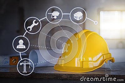 The yellow safety helmet put on the blueprint at construction site with icon technology Stock Photo