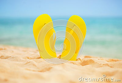 Yellow sandal flip flop on the white sand beach with blue sea and sky background in summer vacations copy space Stock Photo