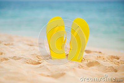 Yellow sandal flip flop on the white sand beach with blue sea and sky background in summer vacations copy space Stock Photo