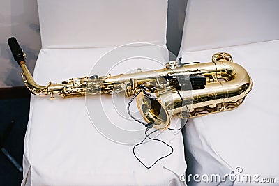 Yellow saxophone lies on a chair. The musical instrument lies close up Stock Photo