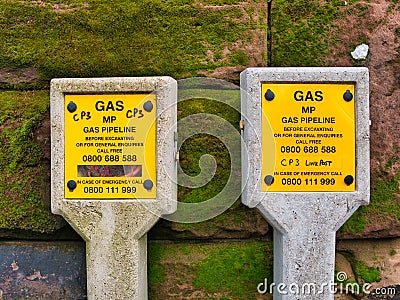 Yellow signs on concrete posts warn of Medium Pressure MP gas pipelines in an urban area in the north west UK Editorial Stock Photo