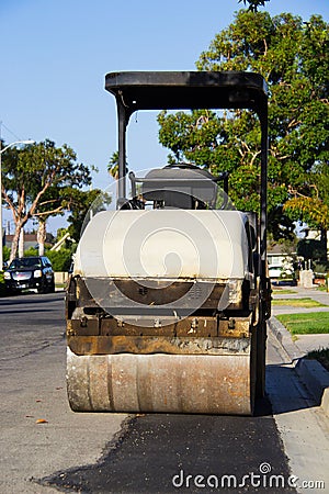 Yellow smooth drum roller parked in a residential neighborhood. Stock Photo