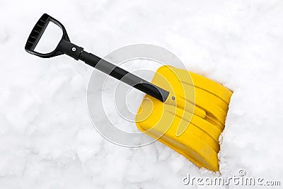 Yellow snow shovel on snow Stock Photo
