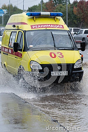 Emergency Ambulance Reanimation Medical vehicle driving on road over muddy puddle, splashing wat Editorial Stock Photo