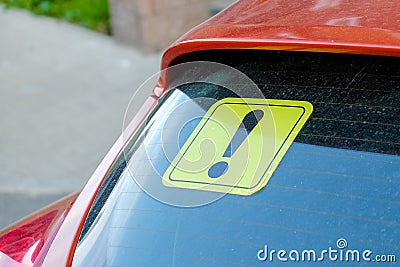 Yellow sticker with an exclamation point on the car`s glass. A newbie driver`s sign Stock Photo