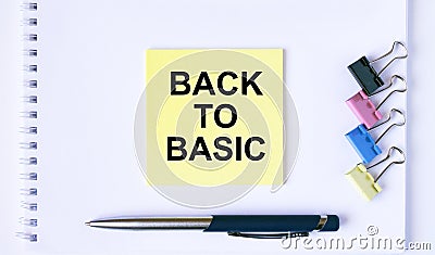 Yellow sticker with text Back To Basic lying on a white Notepad with a pen and paper clips Stock Photo