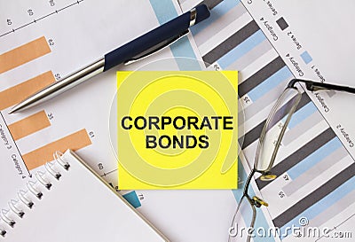 Yellow sticker with text Corporate Bonds lies on financial charts with pen and eyeglass Stock Photo