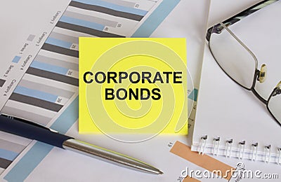 Yellow sticker with text Corporate Bonds lies on financial charts with pen and eyeglass Stock Photo