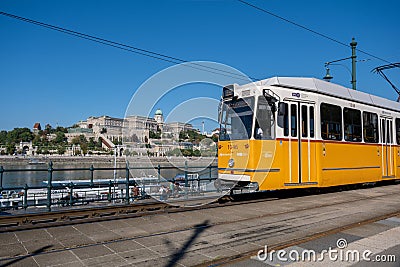 A yellow streetcar in downtown Budapest, with Buda Castle in background Editorial Stock Photo