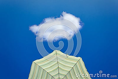 Yellow striped parasol against bright blue sky with one cloud Stock Photo