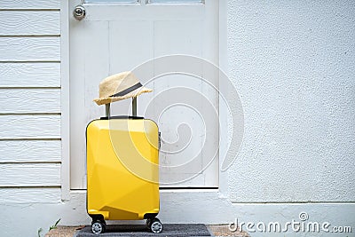 Yellow suitcase, luggage with hat at front door, Leaving home for a holiday and vacation, travel, get ready for adventure Stock Photo